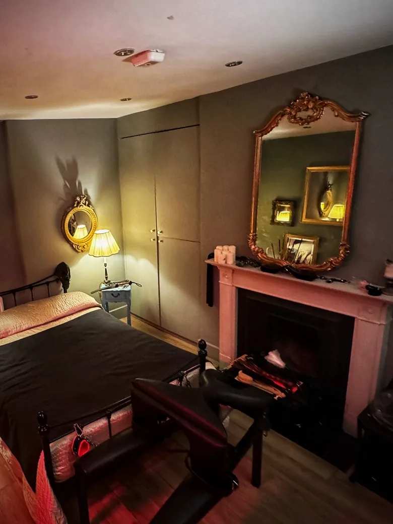 The Chapel: a gilded mirror above a fireplace, candlelight and a bed dressed in black