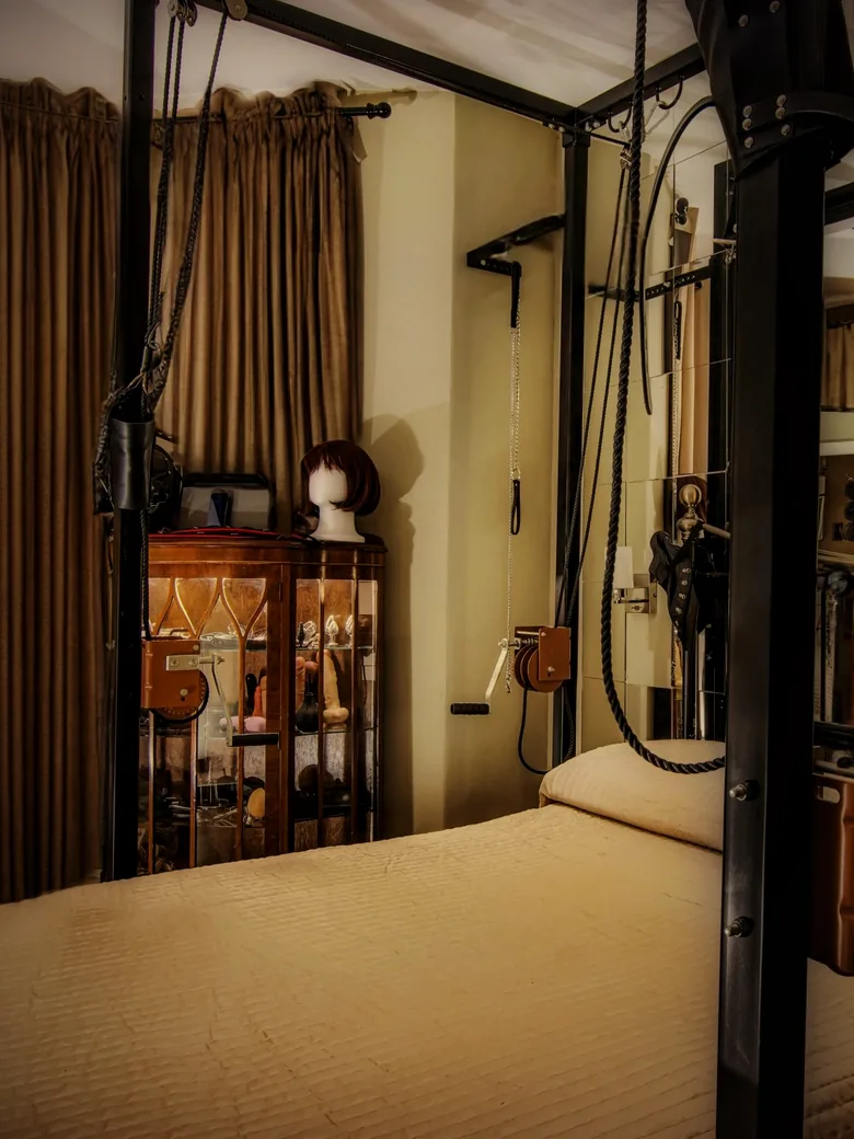 The Vestry: a heavy curtain, a cabinet of masks and a steel frame above the bed